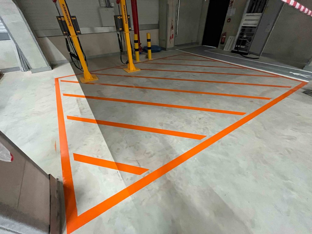 Auf dem Boden sieht man eine klare deutliche Bodenmarkierung in orange.